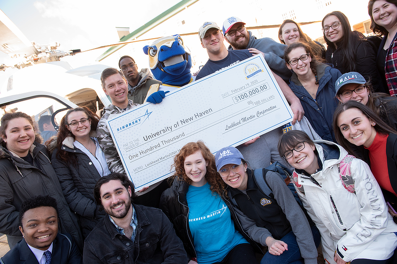 A group photo with a large donation check in the center.