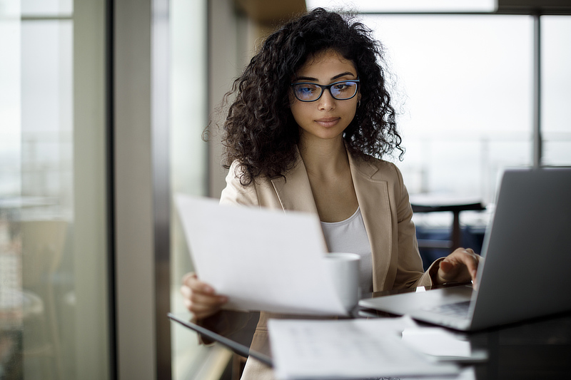 An employer referencing her material while working on her computer.