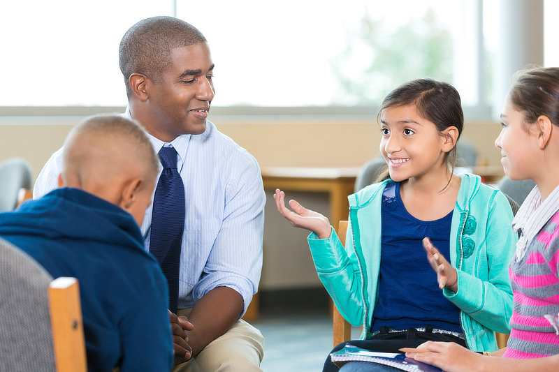 A counselor is holding a discussion with a group of students.